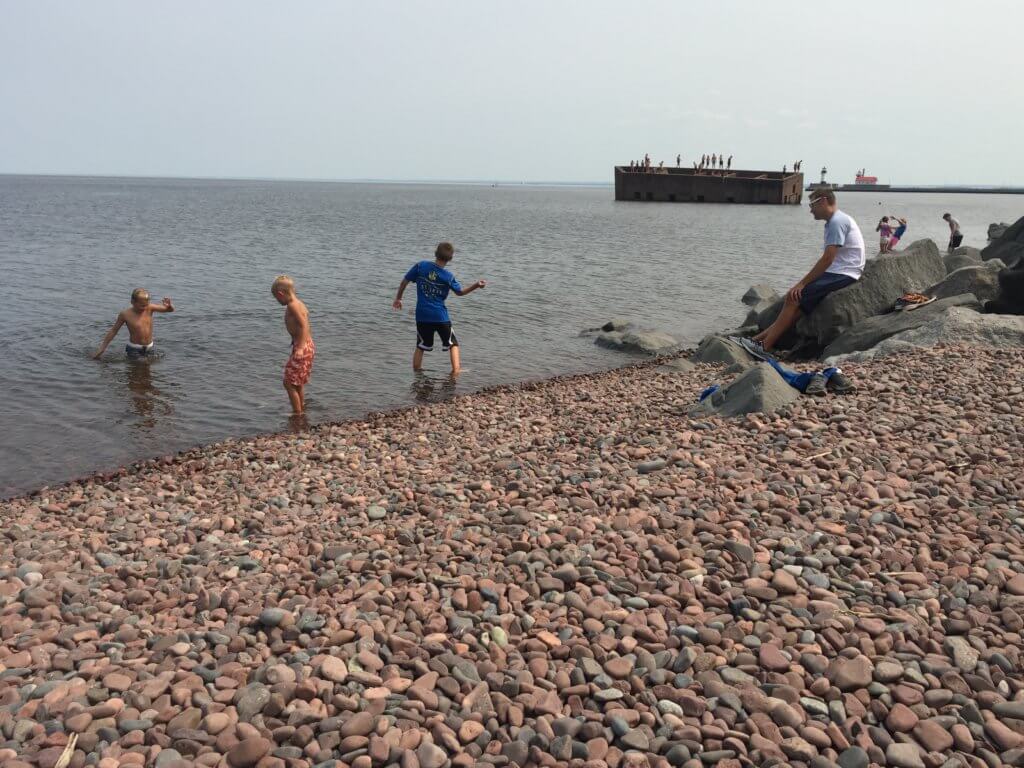 The Best Things to Do in Duluth MN with your Family featured by top US family travel blog, Travel with a Plan: image of Boys skipping rocks along the Lakewalk