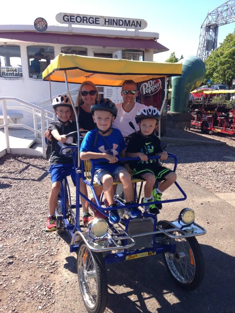 The Best Things to Do in Duluth MN with your Family featured by top US family travel blog, Travel with a Plan: image of a Family on a Wheel Fun surrey rental