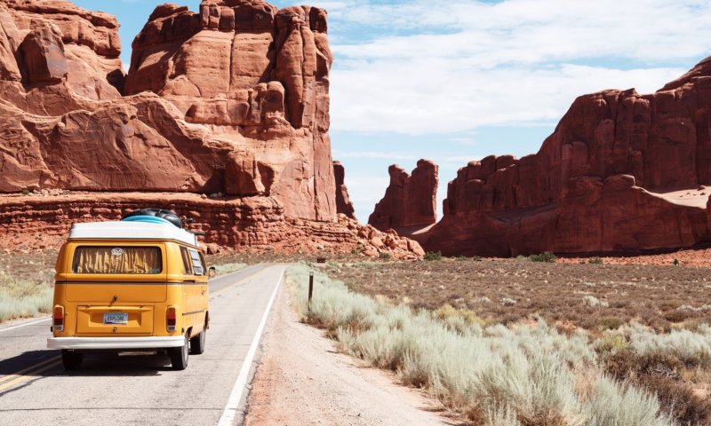 Best travel products featured by top US family travel blog, Travel With a Plan: Yellow van driving alongside mountains