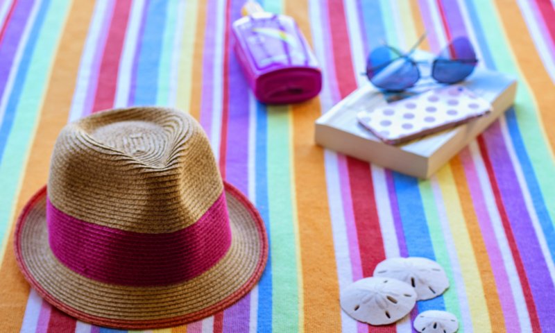 Beach towel with hat, book, and sunglasses